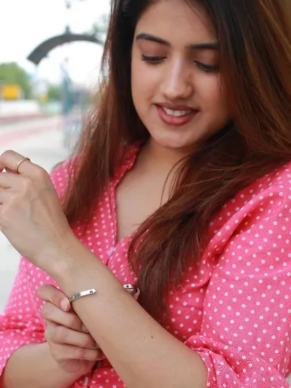 A close-up of the woman adjusting her silver cuff, demonstrating its comfortable and adjustable fit for all-day wear.