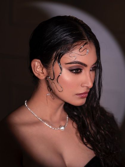 A profile shot from the wet-look series, where the light creates a beautiful rim effect around the model's face and hair. This highlights her silhouette and the delicate pearl details.