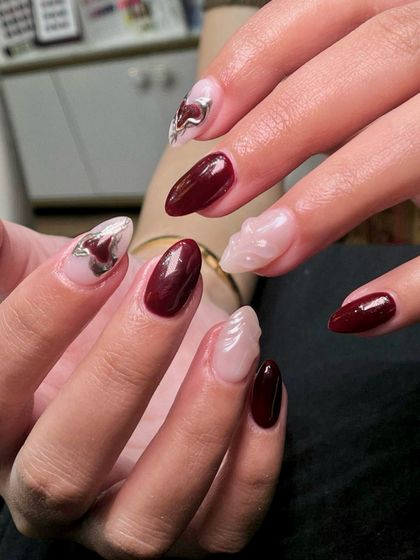 A side view showcasing the dimension of the sculpted nail and the glossy finish of the maroon polish.