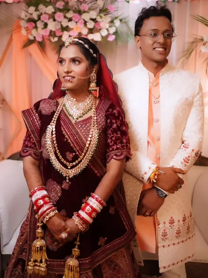 The couple posing together, showcasing the rich details of the bride's velvet lehenga and the groom's sherwani.