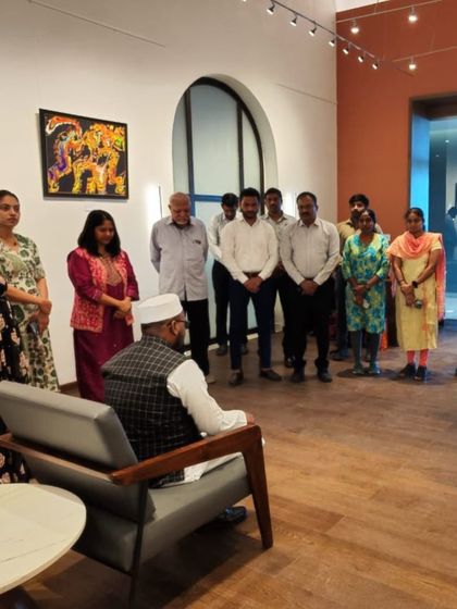 A group of guests listening to a talk at the opening of the 'Surreal Strokes' exhibition.