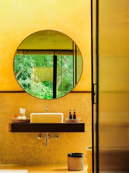 The bathroom vanity, where a round mirror reflects the forest outside, bringing the outdoors in even in the most private moments.