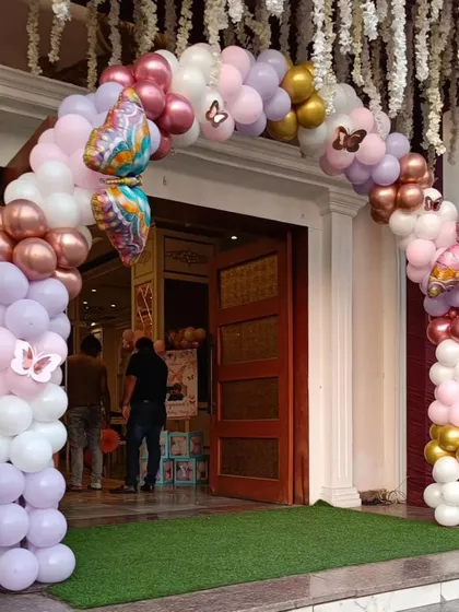 A beautiful balloon arch in pastel pinks, purples, and golds, accented with butterfly foils, creates a magical entrance for a butterfly-themed party.
