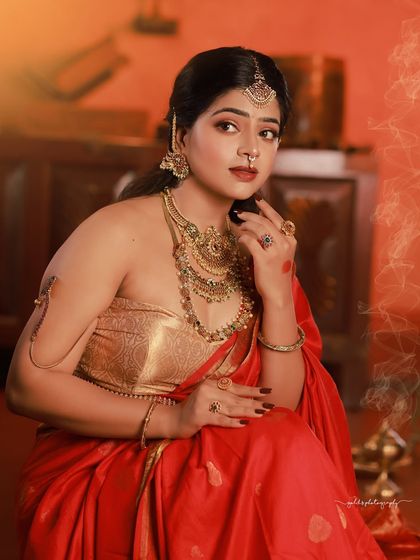 A regal portrait series inspired by the queens of Tulunadu. The model is adorned in a stunning red saree and antique-style jewelry, captured in a heritage location to enhance the royal theme.