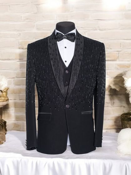This is a full view of my black sequined tuxedo on a mannequin. The design shows a gradient of beadwork from the shoulder down, creating a sparkling texture that catches the light, perfect for a gala or stage performance.