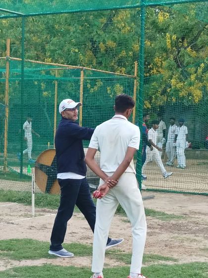 A young bowler gets direct instruction on his technique from Virender Sehwag. This hands-on approach ensures that fundamental skills are corrected and perfected early on.