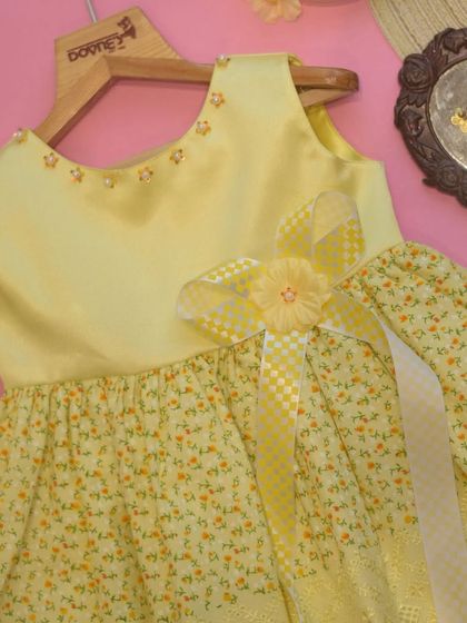 A sunny yellow dress perfect for summer. This piece combines a solid satin bodice with a lightweight floral and embroidered skirt for a fresh, cheerful look.