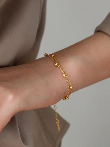 A delicate double-strand beaded bracelet in gold-toned stainless steel. This piece is lightweight and adds a lovely, subtle detail to your wrist.