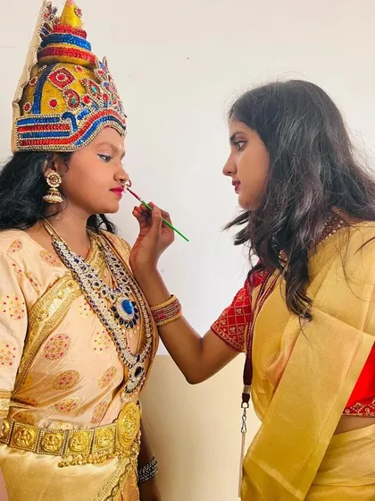 Here I am carefully applying makeup for a goddess performance. This look required detailed work around the eyes and lips, designed to complement the ornate South Indian temple jewellery and kireetam.