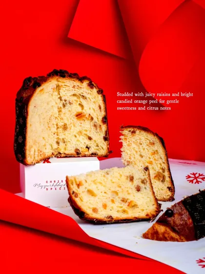 A slice of the Panettone reveals a cloud-like, buttery crumb studded with juicy raisins and bright candied orange peel.