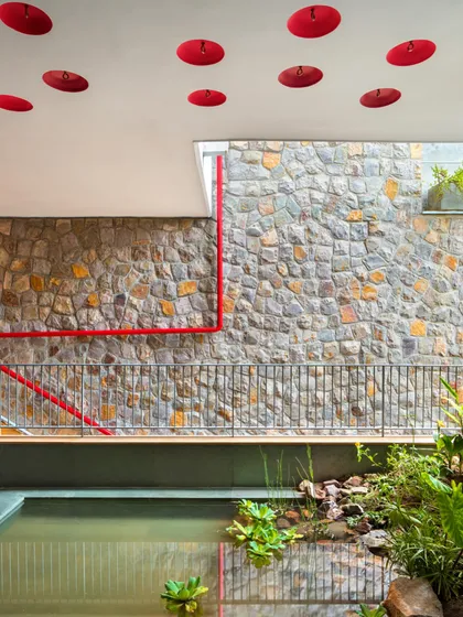This view captures the essence of biophilic design. An indoor pond, filled with indigenous plants, sits below a ceiling dotted with inverted earthen pots, designed to encourage birds to nest and feel at home within the architecture.