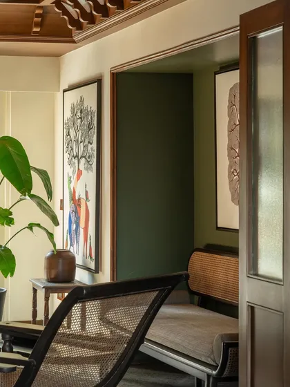 The master lounge, a cozy reading nook with a deep green accent wall. The space is filled with art and comfortable, modern-classic furniture.