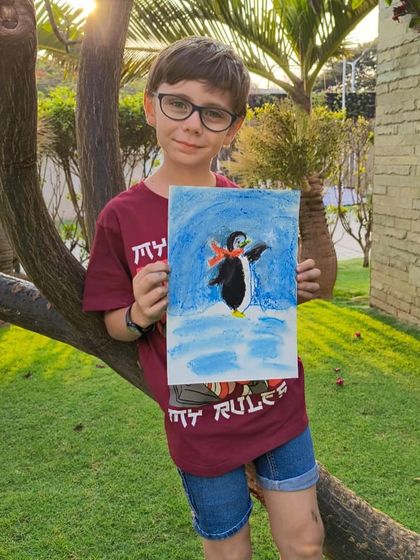 A student from our Prestige White Meadows class poses with his charming penguin artwork.