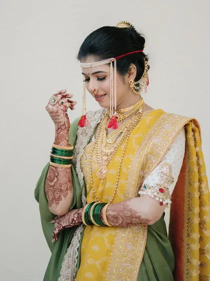 A graceful portrait of the bride admiring her henna-adorned hands. This shot highlights the intricate details of her bridal look, from the mundavalya to the mehndi.