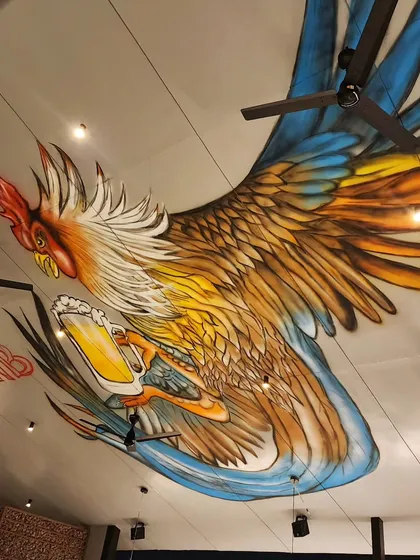 Why limit art to walls? For Plan B in Kammanahalli, we painted this huge, dynamic rooster mural directly onto the ceiling, creating an immersive and unexpected art experience for diners.