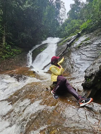 A trekker sitting on a rock, enjoying the cool spray of Hidlumane falls.