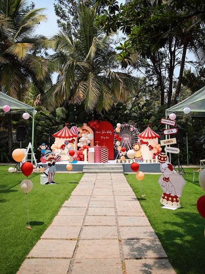 A fun circus-themed birthday party at Farmhouse Collective. The bright red and white decor, complete with a Ferris wheel backdrop, transforms the lawn into a carnival.