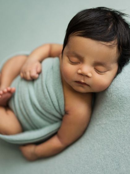 Another variation of the side-lying pose, with the baby gently wrapped in a soft blue swaddle. This pose is wonderful for showing off their profile and chubby cheeks.