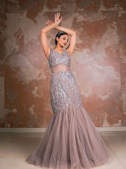 This pose showcases the full silhouette of the mermaid gown. The model's arms create a beautiful frame, drawing attention to the intricate beadwork and the elegant fall of the tulle skirt.