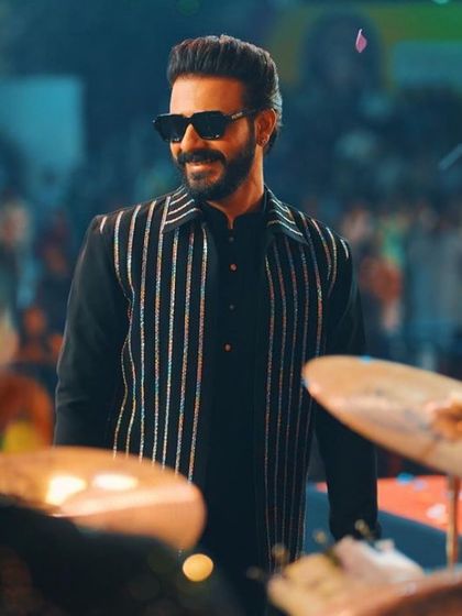 Style in the spotlight. Musician Naitik Nagda looks effortlessly cool in our custom black kurta and striped bandi jacket ensemble.
