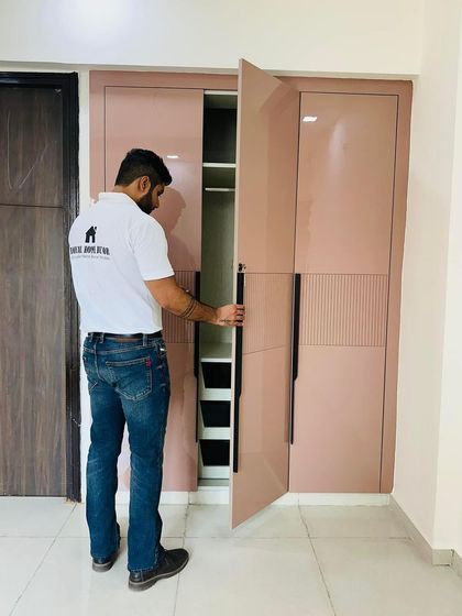 Another angle of the dusty rose wardrobe, showing the hinged doors and the seamless finish. This custom piece provides floor-to-ceiling storage, maximizing the available space.