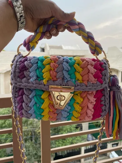 This is my crochet "marshmallow" bag in a vibrant rainbow design. It's made from soft T-shirt yarn and is surprisingly lightweight, with a chunky gold chain that makes it a real statement piece.