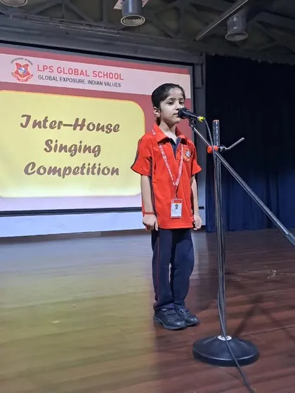 A young boy stands at the microphone, ready to represent his house in the singing competition. We provide a supportive environment for students to overcome stage fright and perform their best.
