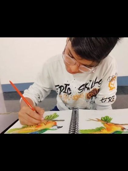 A young artist completely absorbed in his watercolor painting, showcasing the focus that art inspires.