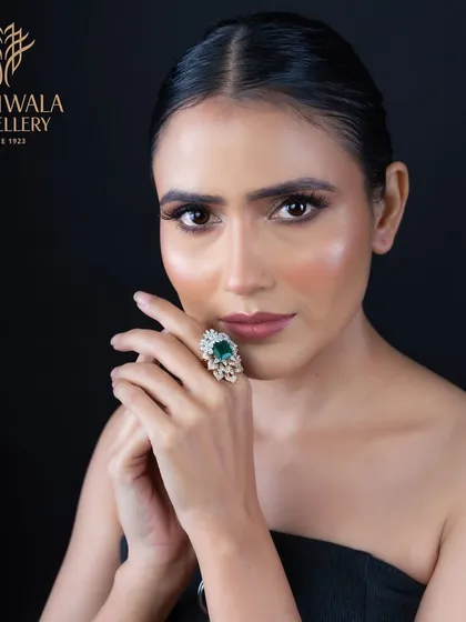 A regal statement piece. This ring features a large, pear-shaped emerald surrounded by a floral halo of brilliant diamonds, designed to capture attention and admiration.