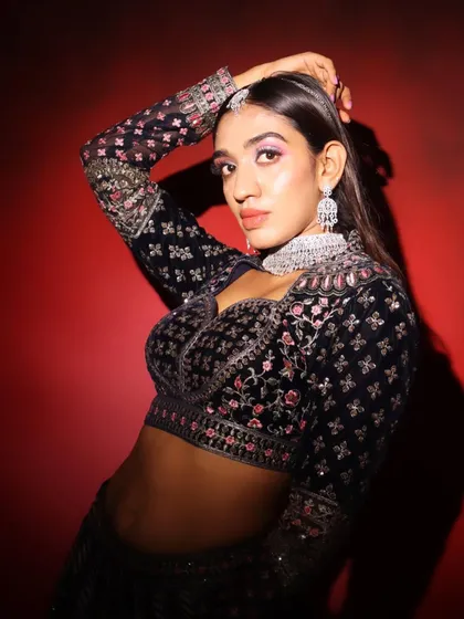 A high-fashion pose showing off the edgy makeup and the intricate details of the designer blouse.
