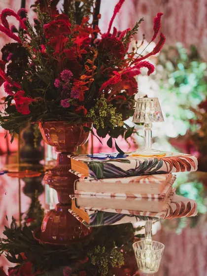 A reflection shot of the table decor, showcasing the vibrant red florals and the custom-wrapped books.