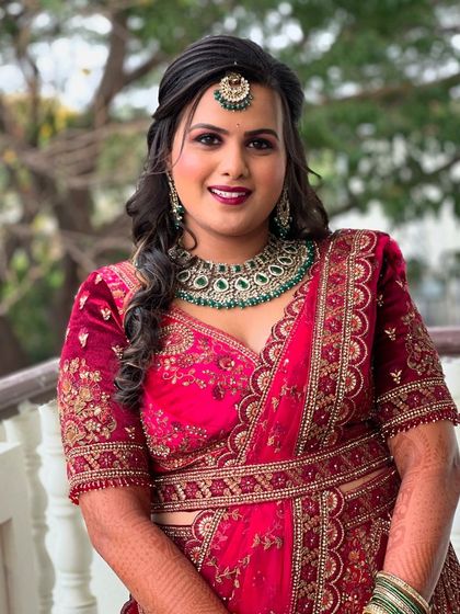 A full view of Supriya's reception look. The makeup is designed to stand out and complement her ornate red and green jewelry.