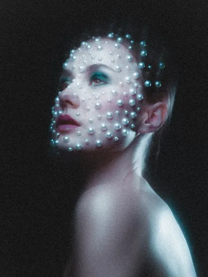 Another angle of the pearl makeup, looking upwards into the light. This pose highlights the shimmer on the skin and the careful arrangement of the pearls across the facial contours.