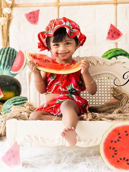 A happy baby enjoying a slice of watermelon in a setup filled with the fruit. Using real elements makes the photos feel more authentic and engaging.