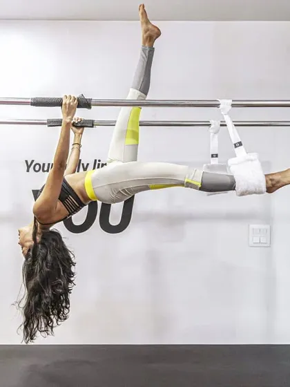 The Cadillac allows for incredible movements that decompress the spine and build upper body strength. This inverted pose combines flexibility and control, showcasing the transformative power of advanced Pilates.