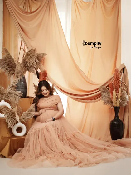 A slightly different angle of the same beautiful setup, capturing a gentle smile. The layers of fabric and pampas grass add so much depth and texture to the photo.