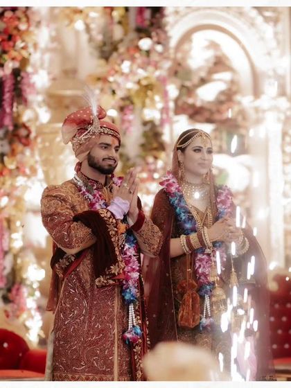Akhilesh and Nisha on stage during the Varmala ceremony, with sparklers going off, creating a grand and festive moment.