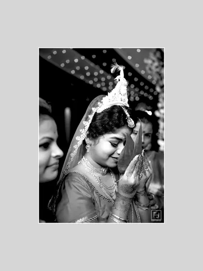 The 'Vivahhh' is filled with moments of deep devotion. This black and white photograph of a Bengali bride during a ritual captures the serenity and grace of the ceremony. Using monochrome strips away distractions, focusing solely on the emotion and tradition of the moment.