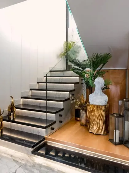 This staircase is a masterpiece of design. The combination of black marble steps with integrated lighting, a glass railing, and elegant decor creates a stunning focal point.