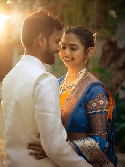 A romantic portrait of a couple during golden hour, the warm light beautifully highlighting their traditional attire and happy expressions.