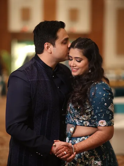 A tender moment between the couple, sharing a sweet kiss on the forehead, captured during their Sangeet celebration.