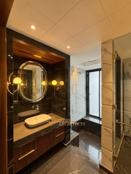The walk-in shower is enclosed in glass, maintaining the open and airy feel of the bathroom while showcasing the beautiful contrast between black and white marble.