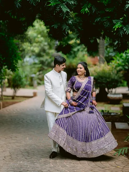 A playful and elegant moment as Rutwij leads Apeksha, her stunning purple lehenga swirling around her. This image captures the grandeur and joy of their engagement day.
