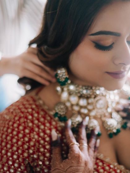 A close-up of the bride getting her necklace adjusted. This captures the final touches and the anticipation of the getting-ready process.