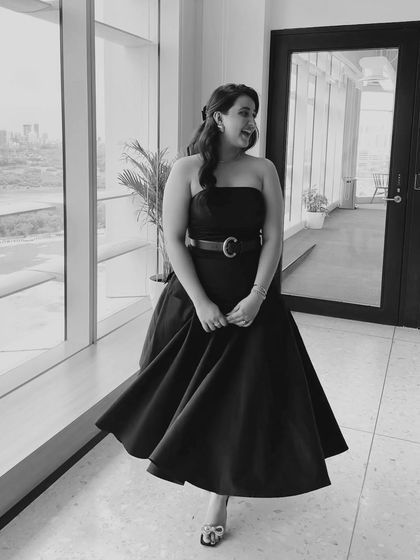 A candid black and white shot of one of the Kota Factory actors, dressed in a timeless, elegant black dress.