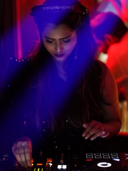 A moody, blue lit shot of me focused on the mixer at Publik, Kolkata, showcasing the more intense side of my sets.