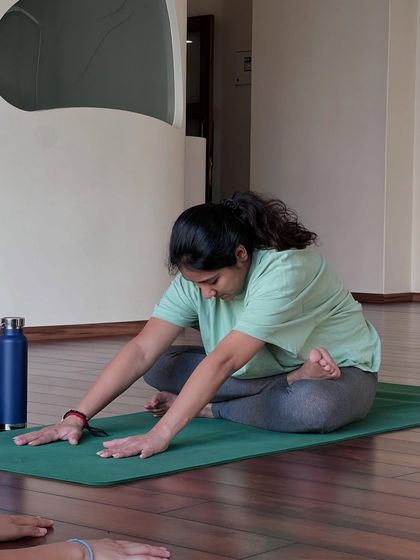 A student practices a gentle forward bend, a modification of Janu Sirsasana. This helps to stretch the hamstrings and back while creating space for the belly.