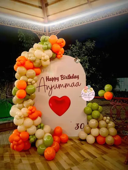 A unique 30th birthday setup with a custom backdrop and an organic balloon garland in orange, green, and white.