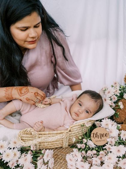 A close-up of the three-month-old baby girl, surrounded by flowers. These milestone sessions are a wonderful way to document their growth.