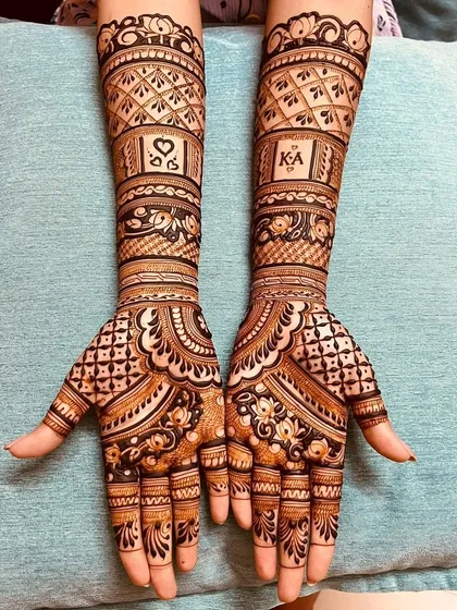 This engagement mehndi features personalized initials 'KA' and a heart, surrounded by detailed jaali (net) and floral patterns. We can incorporate any element that is special to you as a couple.
